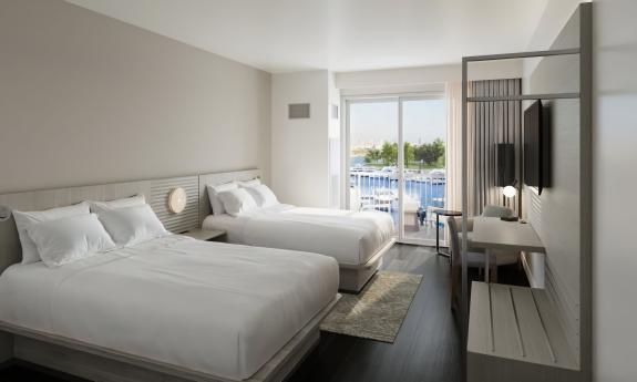 A hotel room with two queen beds and a balcony, decorated in a soothing palette