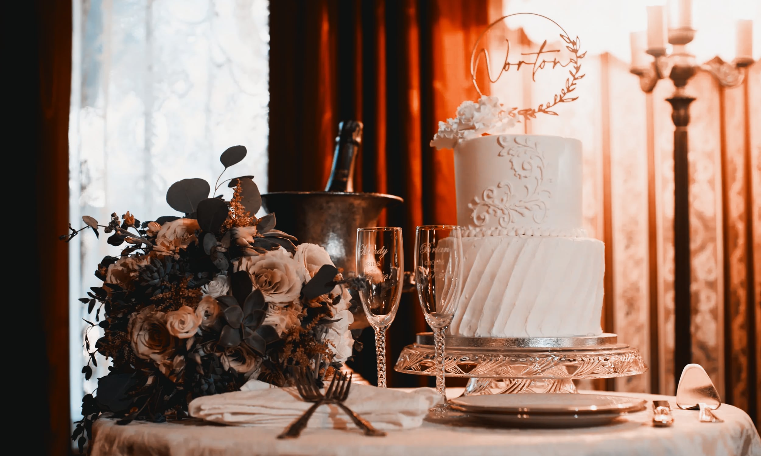 Wedding table setup at Cedar House Inn including a two-tier wedding cake, Champagne, flute glasses, and a bouquet arrangement