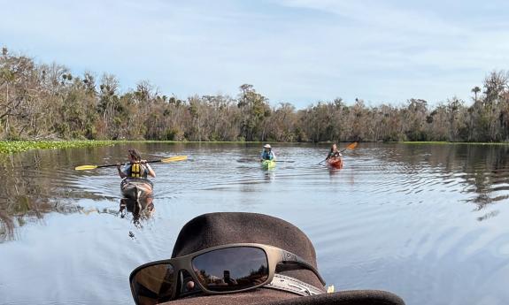 Kayakers following their guide, seen only by his hat in the foreground