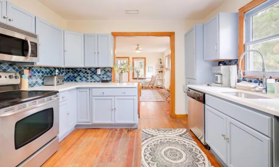 This blue-painted kitchen has warm wood tones on the floor and trim