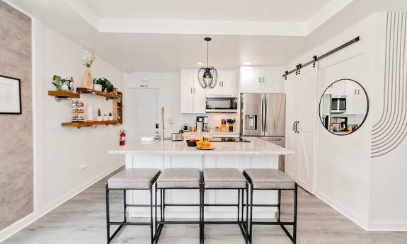 A kitchen and dining counter with white walls and tan and orange accents