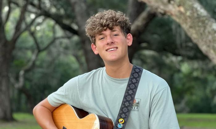 Guitarist Hudson Vance with his guitar, outside