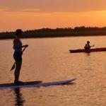 A kayaker and a paddle boarder enjoying sunset over the river in St. Augustine.