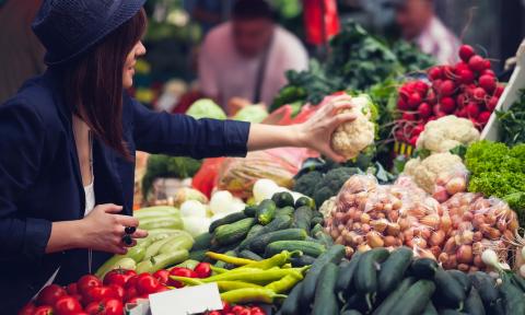 A marketgoer picking up produce at a stand