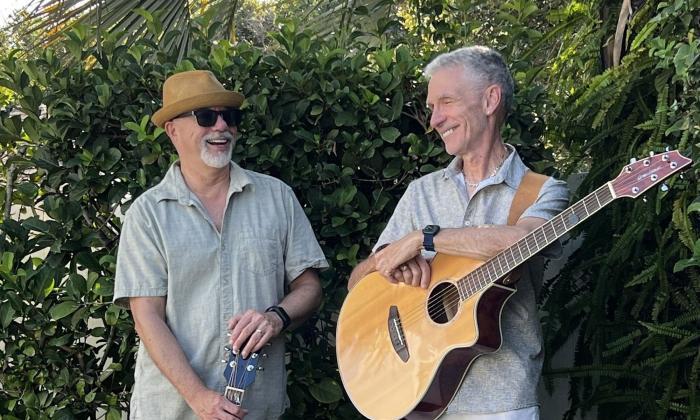 The duo Little Silver standing with guitars in front of hedge, both smiling