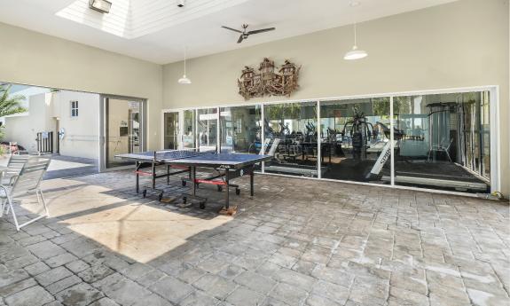 The fitness center at Ocean Gallery opens to an enclosed patio with a game table