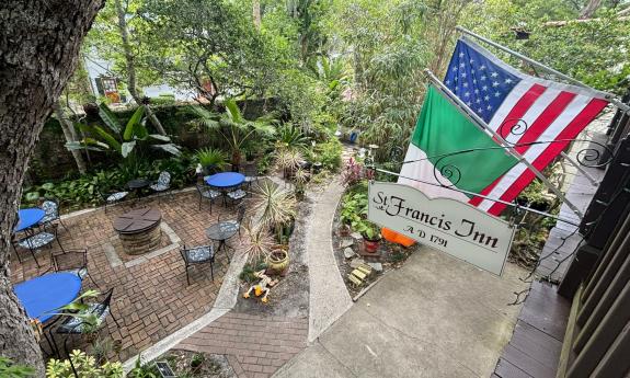 The courtyard at St. Francis Inn, from the 2nd floor balcony, with a sign and flags