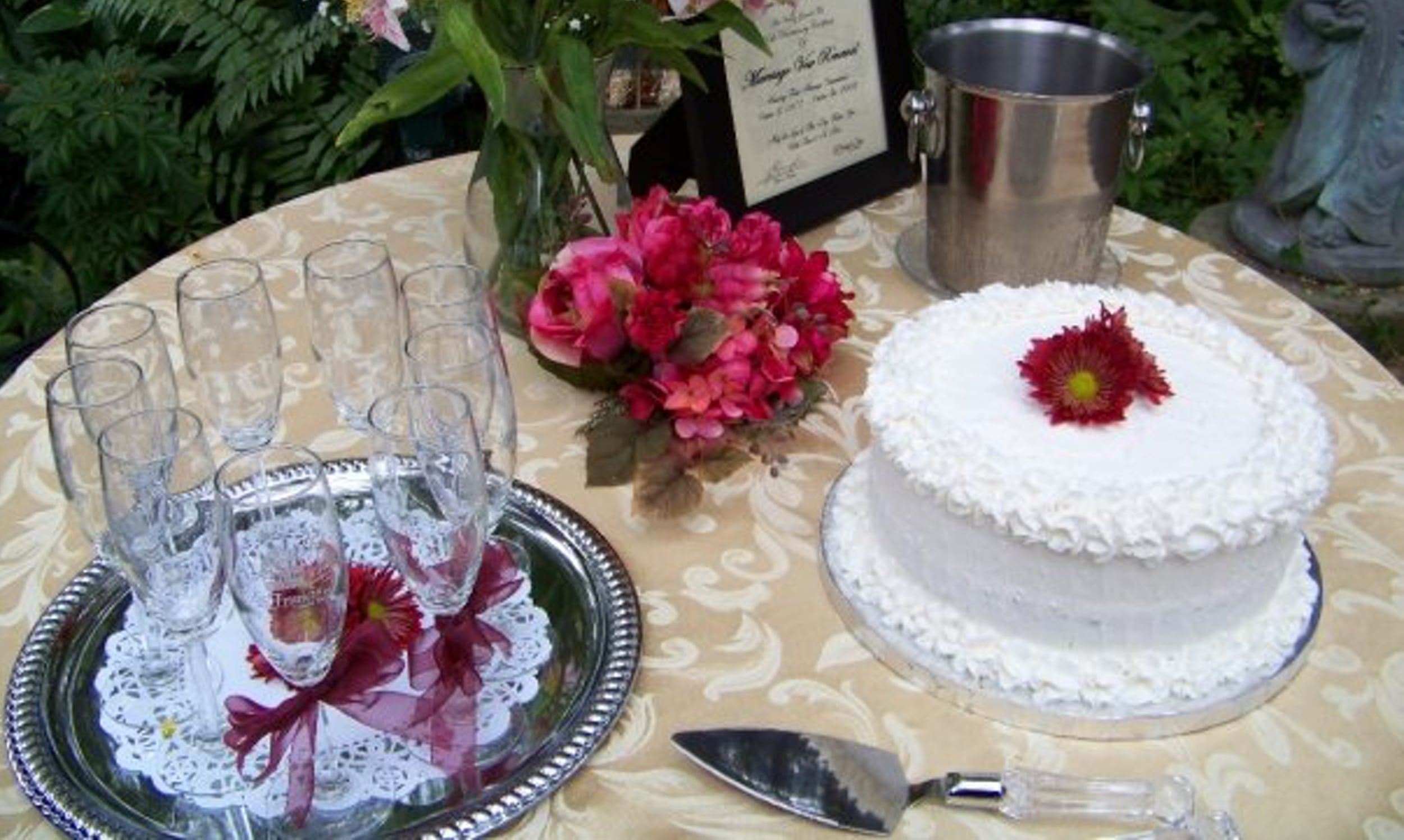 Wedding cake table at St. Francis Inn featuring a flower arrangement, a single tier cake with a flower centerpiece, and a tray of champagne flutes