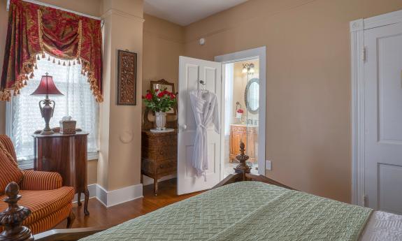 A view from the the bed shows a comfortable seat by the window and the door to the plush bath